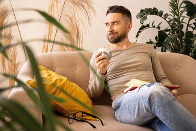 Portrait of young man sitting on sofa at home