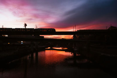 Silhouette bridge over river against sky during sunset