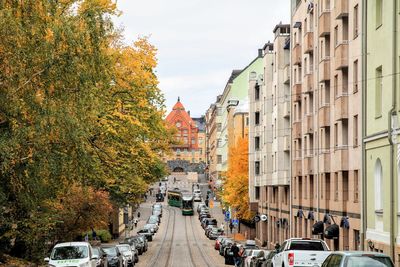 Cars on road amidst buildings in city during autumn