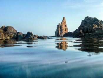 Rock formations in sea against blue sky