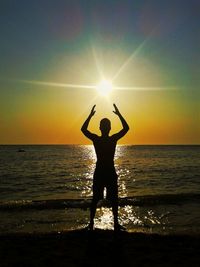 Silhouette man standing at beach against sky during sunset