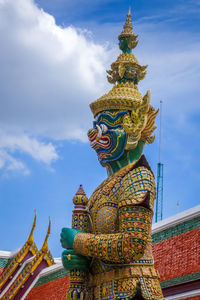 Low angle view of statue against temple building against sky