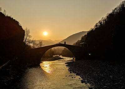 Bridge over river against sky during sunset