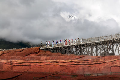 People on bridge against sky