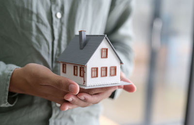 Midsection of man holding house against building