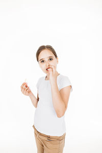 Portrait of young woman standing against white background