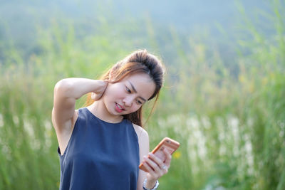 Young woman holding camera on field