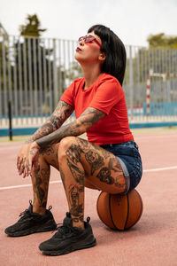 Caucasian girl with tattoos and short black hair on a sports court