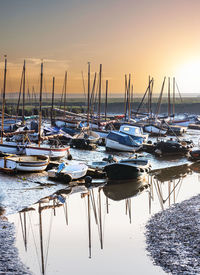 Boats moored at harbor during sunset