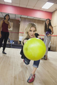 A young woman bowling with friends.