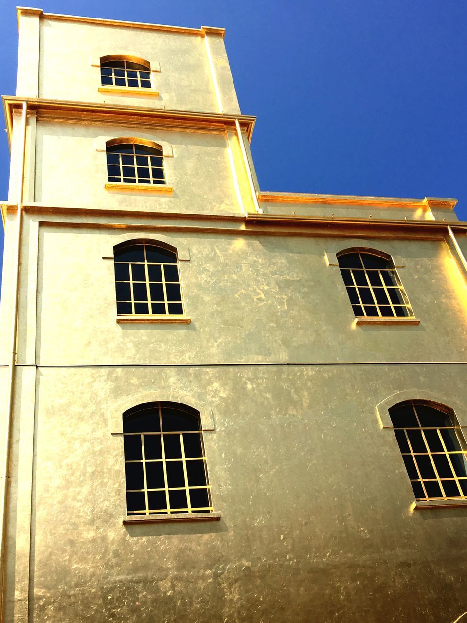 architecture, building exterior, built structure, window, low angle view, building, residential building, residential structure, clear sky, facade, sky, glass - material, day, outdoors, blue, no people, wall - building feature, sunlight, exterior, brick wall