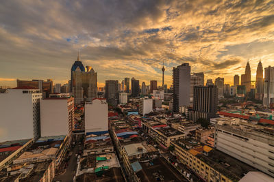 Aerial view of buildings in city against cloudy sky