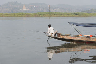 Man sitting on boat moored in lake