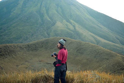 Full length side view of man photographing while standing on mountain