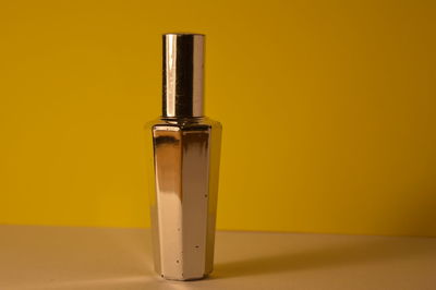 Close-up of yellow container on table against wall