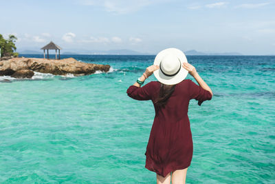 Rear view of woman standing by sea against sky