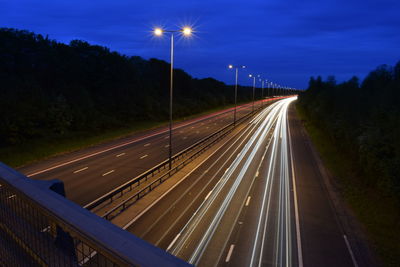 Light trails on road against sky at night