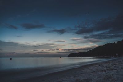 Scenic view of beach against sky at sunset