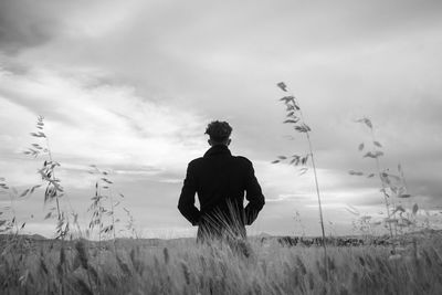 Rear view of man standing on field against sky