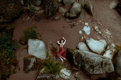 Top view of a woman lying on sand between stones