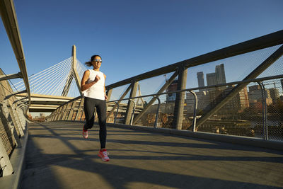 A boston runner running on a footbridge near the zakim bridge.