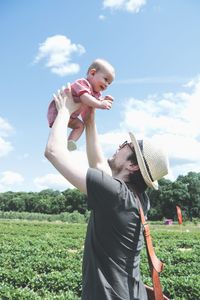 Siblings standing on field against sky