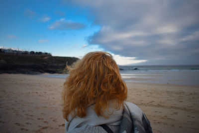 Rear view of woman at beach against sky