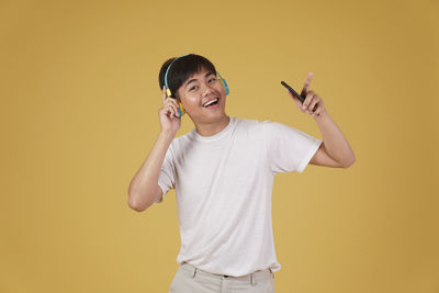 Portrait of a smiling young man against yellow background