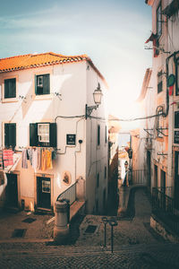 Street amidst buildings in town against sky during sunset