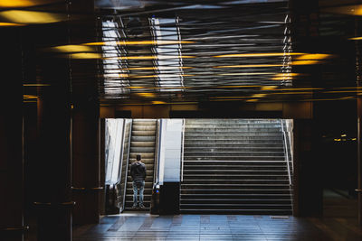 Rear view of man standing on escalator at subway station