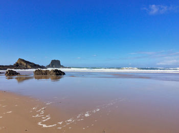 Scenic view of beach against blue sky