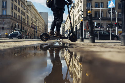 Low section of person with reflection on city street