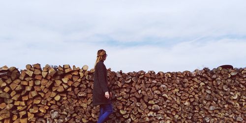 Woman walking by logs against sky