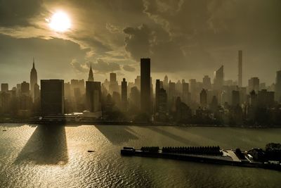 Skyscrapers in manhattan by east river against sky during sunrise