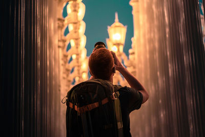 Rear view of man photographing illuminated lights at night