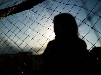 Rear view of silhouette woman on field against sky during sunset