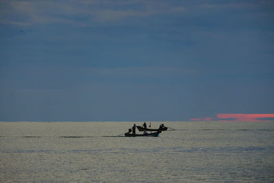 People in boat on sea against sky