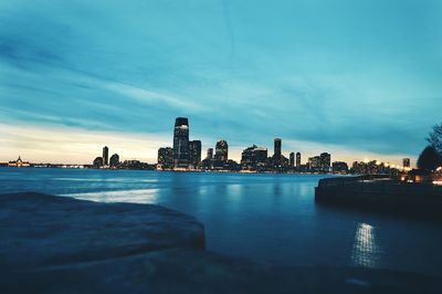 City at waterfront against cloudy sky