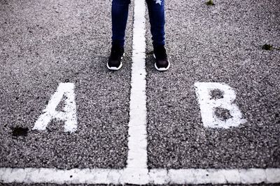 Low section of person standing by alphabets on street