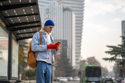 Side view of young man standing against buildings