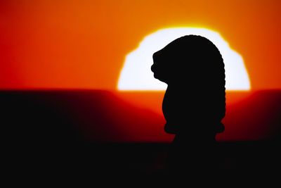 Silhouette woman standing against orange sky