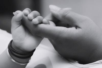 Cropped of baby boy holding mother hand