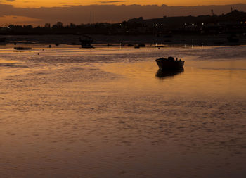 Silhouette boat on shore against sky during sunset