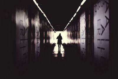 Rear view of silhouette man standing in tunnel