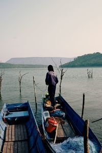 Rear view of men sitting on sea against clear sky