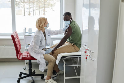 Doctor disinfecting patient shoulder in clinic