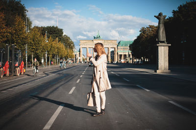 Young woman walking on road against brandenburg gate