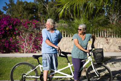 Senior man with woman on bicycle at park during sunny day