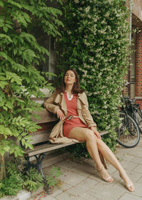 Portrait of young woman sitting on street bench