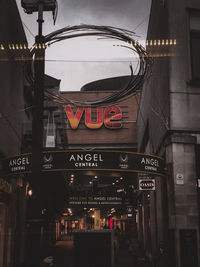 Low angle view of illuminated sign against buildings in city